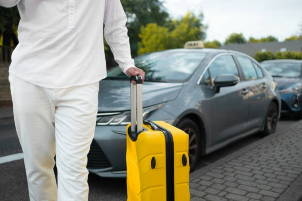 Traveler carrying luggage while getting into an airport taxi
